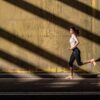 Young fit blonde woman running in the street