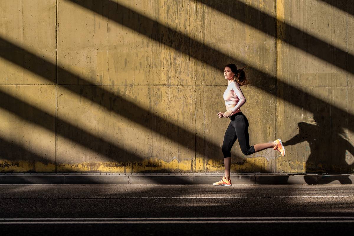 Young fit blonde woman running in the street