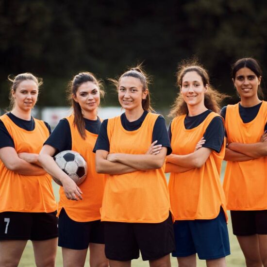 Confident women's soccer team on playing field looking at camera.