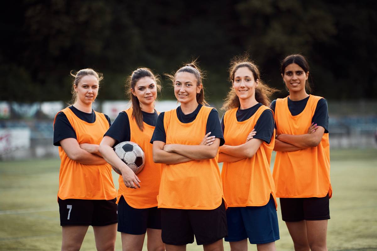 Confident women's soccer team on playing field looking at camera.