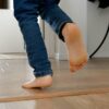 Little boy's energetic feet as he runs along the long wooden corridor in his home. Joys of childhood, playing indoors, and the importance of developing a child's physical abilities.