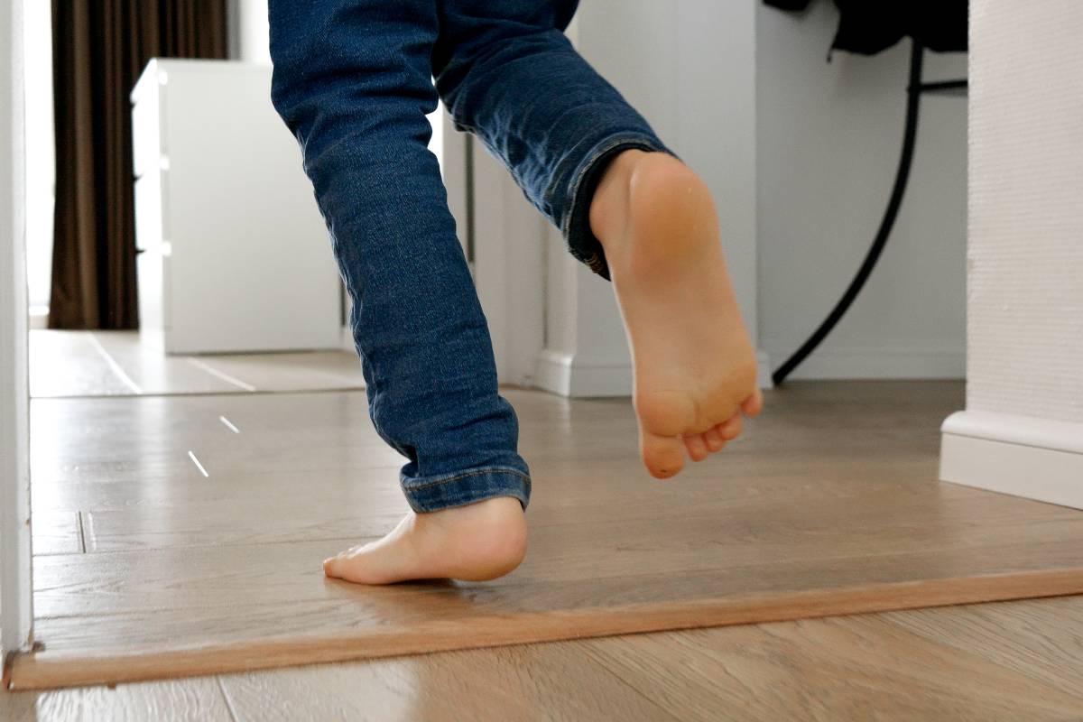 Little boy's energetic feet as he runs along the long wooden corridor in his home. Joys of childhood, playing indoors, and the importance of developing a child's physical abilities.